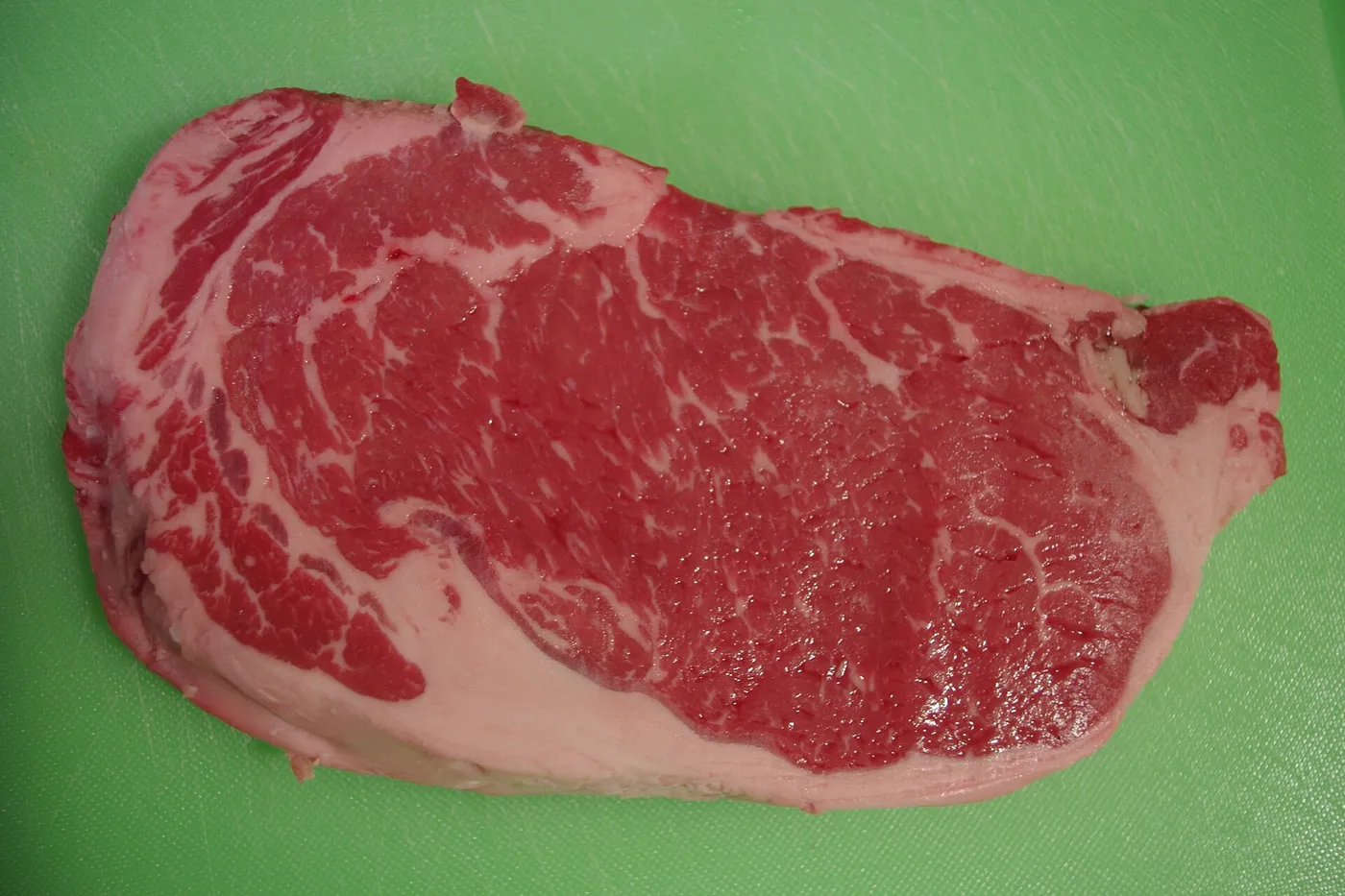 Pièce de bœuf crue sur une planche à découper, prête à être cuite après décongélation